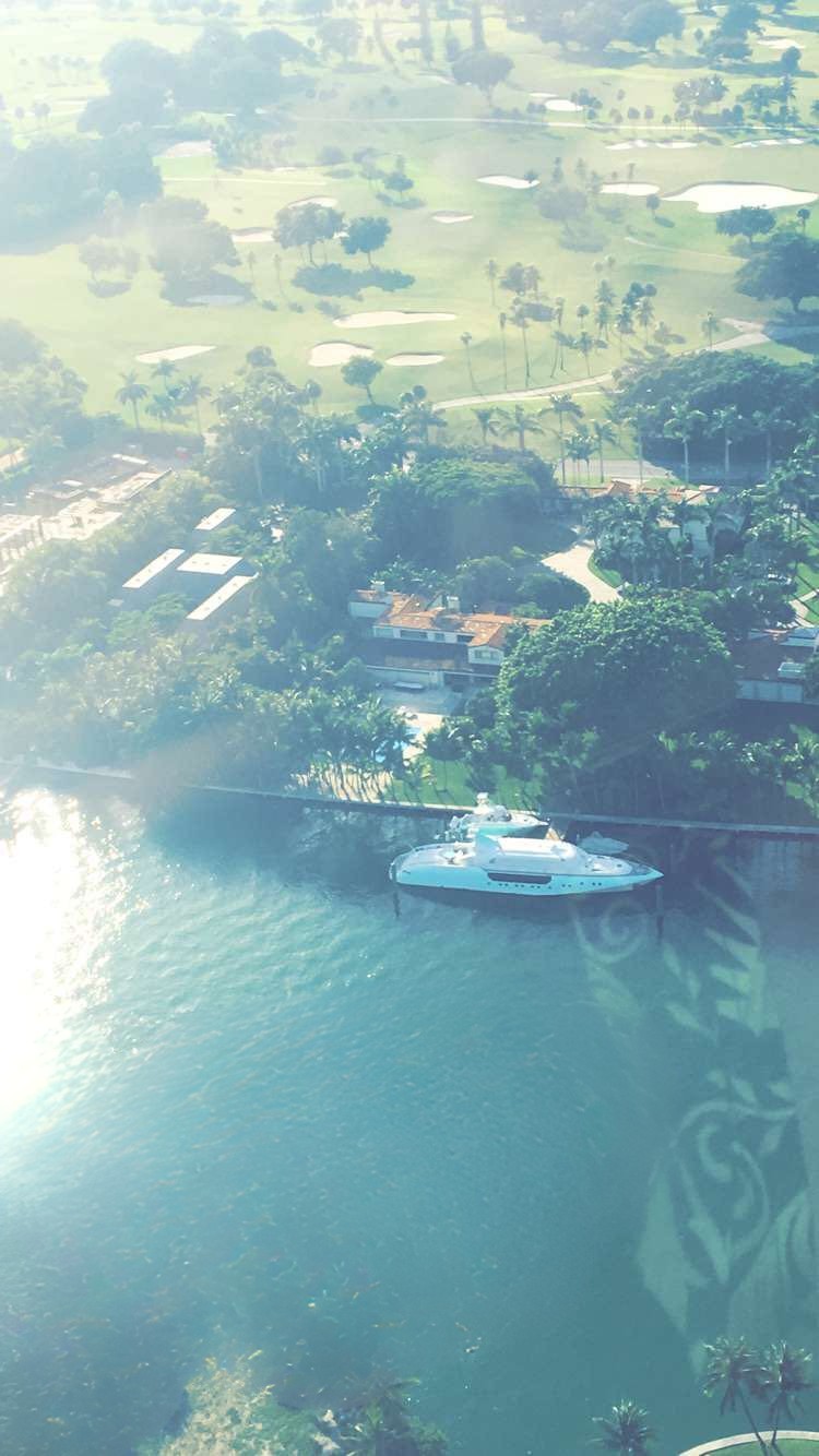 Vue aérienne d’une villa de luxe à Miami avec yacht privé et terrain de golf, prise en hélicoptère